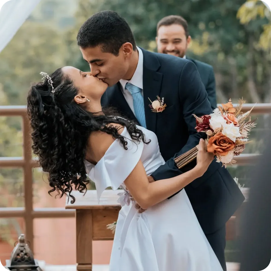 Noivos se beijando com o Daniel ao fundo